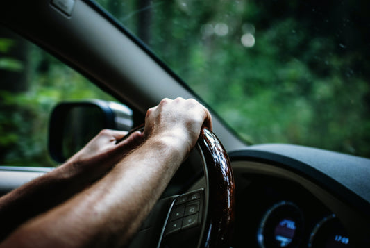 person holding the steering wheel of a car with both of their hands